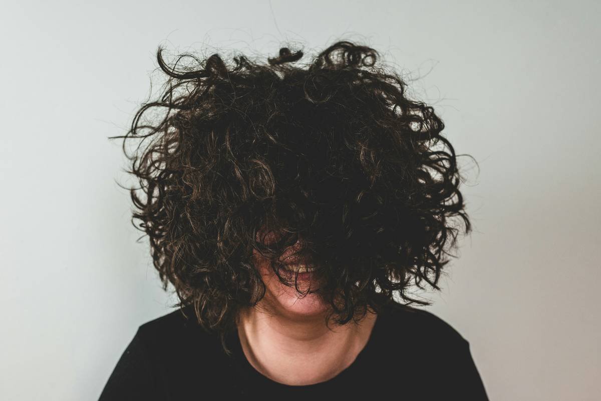 Girl with curly hair in front of her face