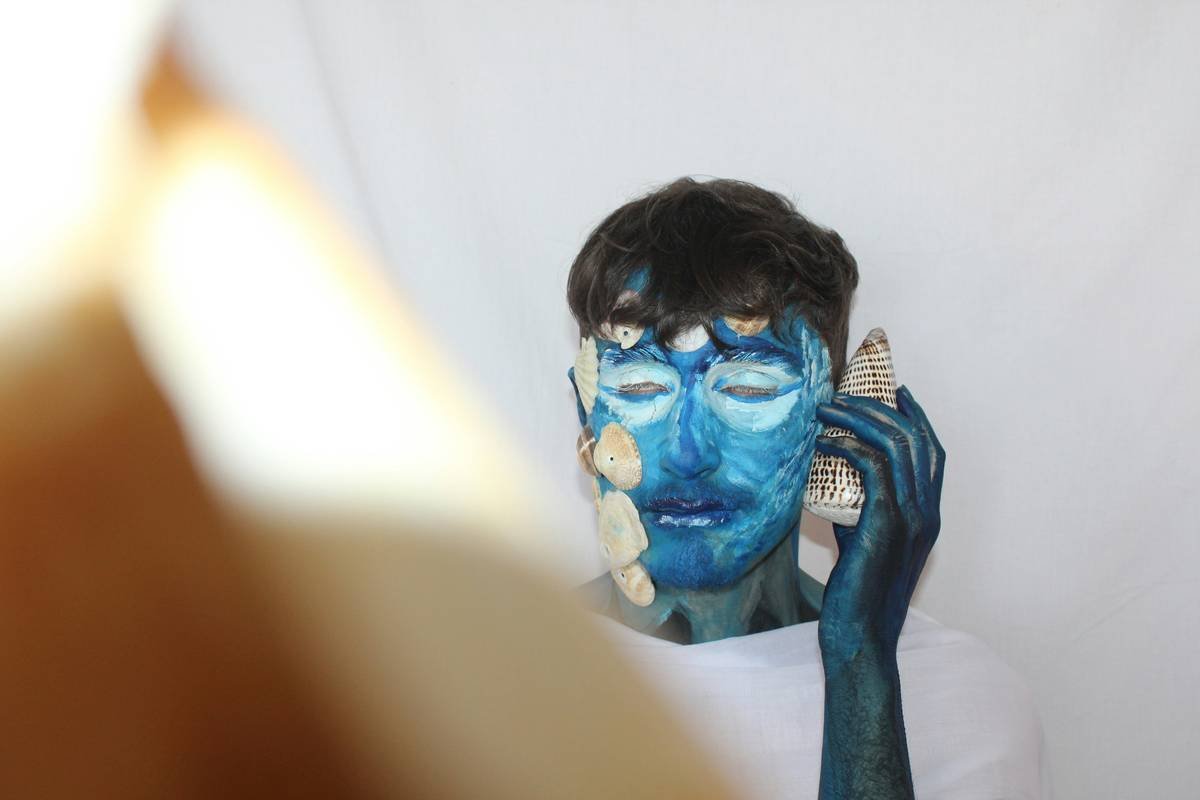 Infographic showing cross-section of layered prosthetic application on face: skin, adhesive, foam latex appliance, stippled paint, translucent powder sealant