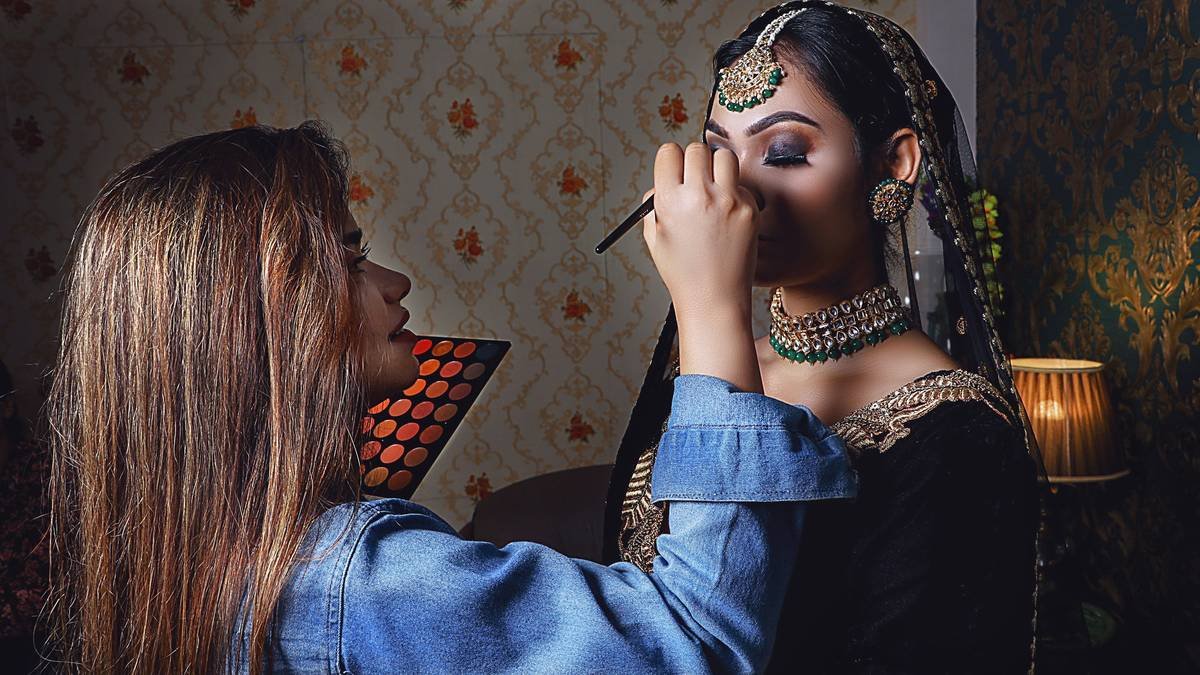 a woman putting makeup on another woman's face
