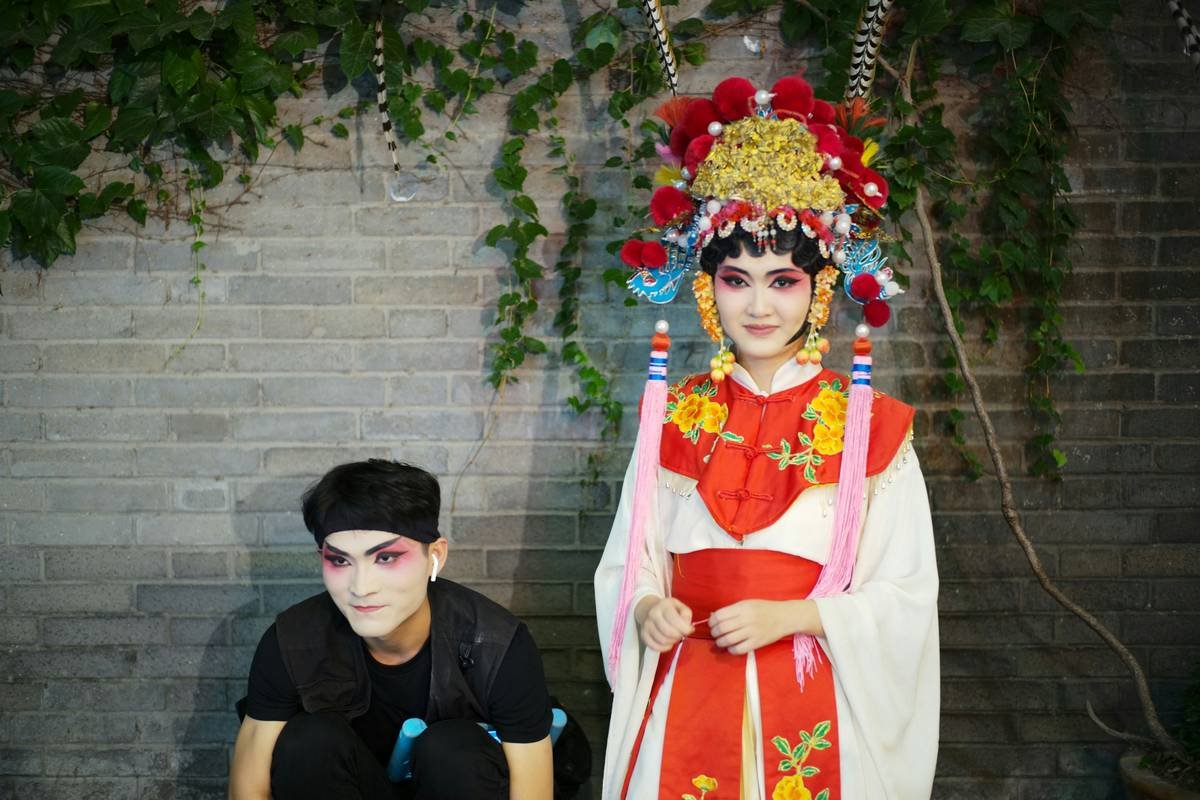 Diagram showing exaggerated facial planes for opera vs. realistic portraiture: cheekbones extended 40%, brow ridges deepened, nose reshaped with shadow to create 3D illusion under stage lights